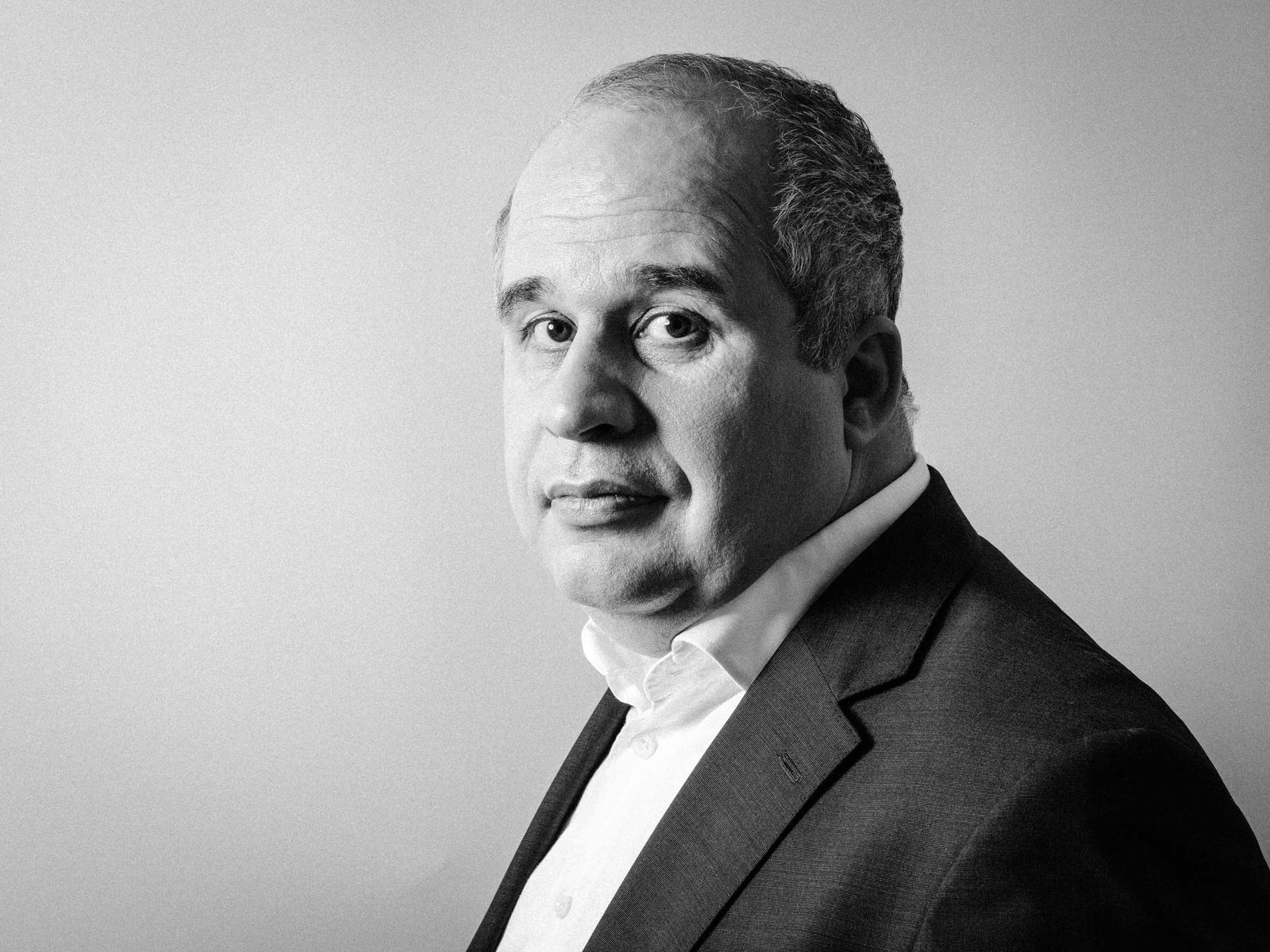 black and white portrait of a middle aged business man looking at you in an enigmatic way.